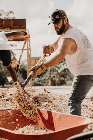 A man shoveling into a wheelbarrow
