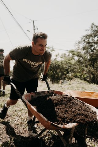 A man pushing a heavy wheelbarrow full of dirt